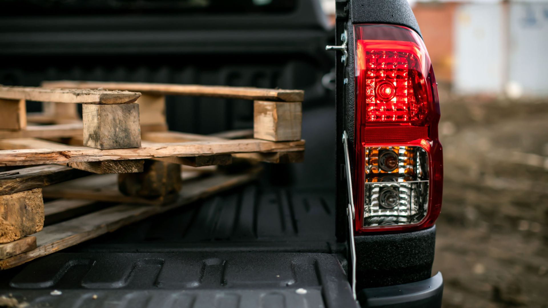 the back end of a pickup truck with wooden pallets in the bed.