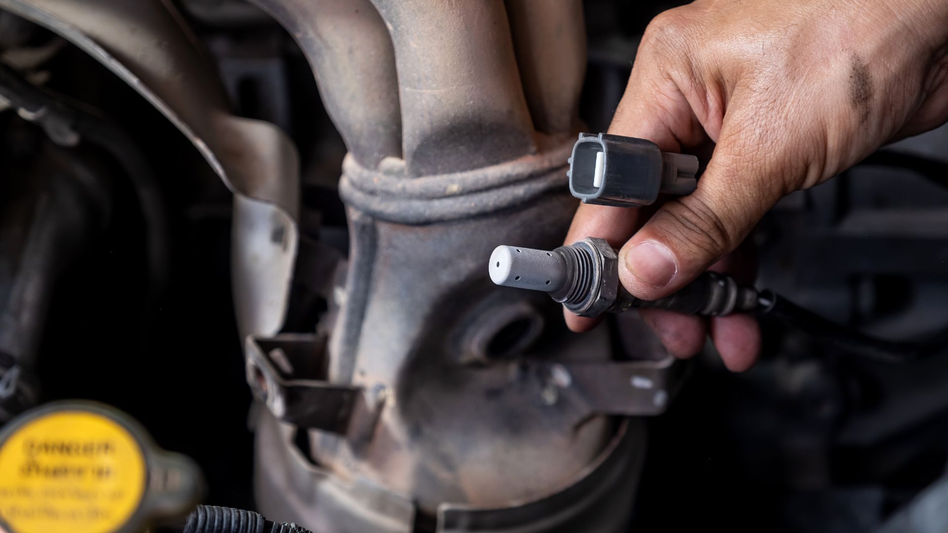 a close up of a person working on a vehicle.|a rusted out car engine with a blue hose connected to it.|a close up of a car engine with a blue hose.