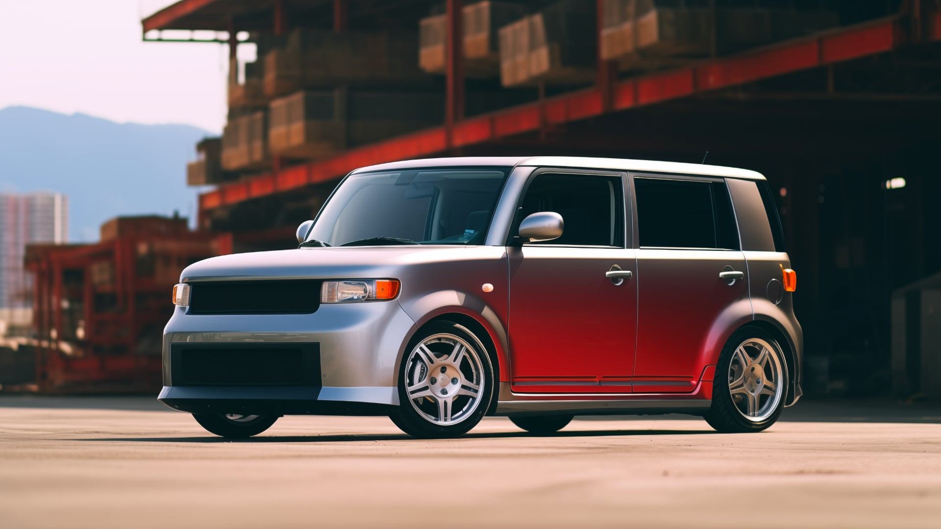 A red Scion xB is parked in front of a building.|a silver car parked on a wet parking lot.