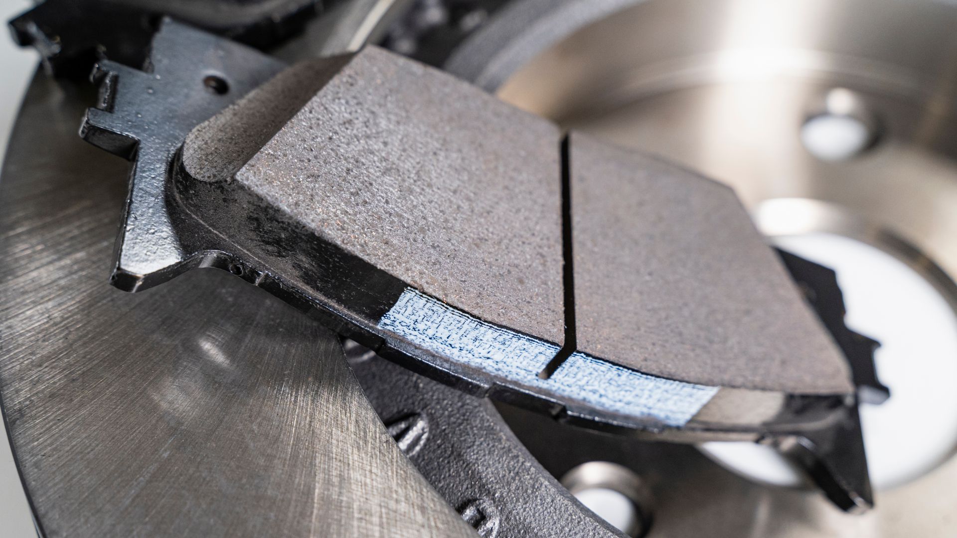 a close up of a brake pad on a motorcycle.|a box of brake pads and tools on a table.|a group of brake pads sitting on top of a table.