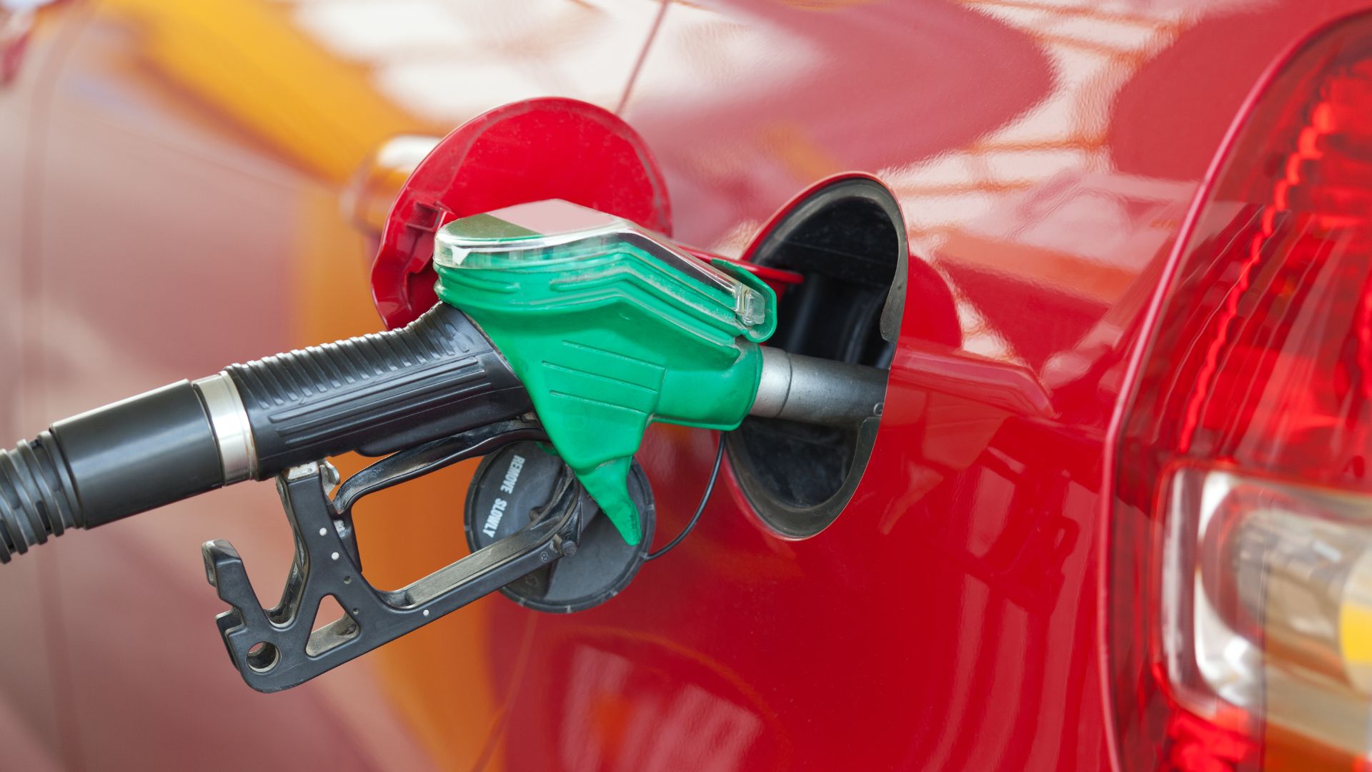 a red car with a green gas pump.|a close up of a speedometer with a red needle.