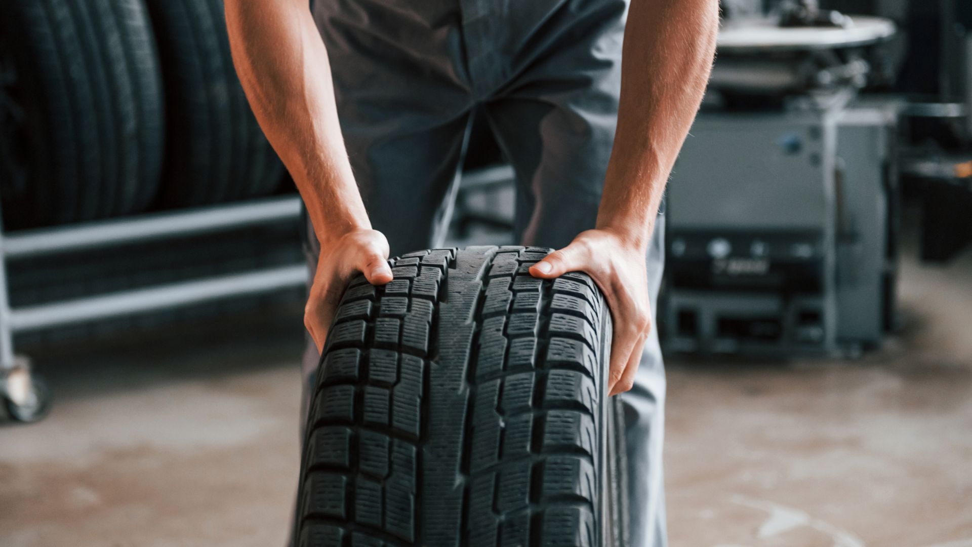 a man holding a tire in a garage.