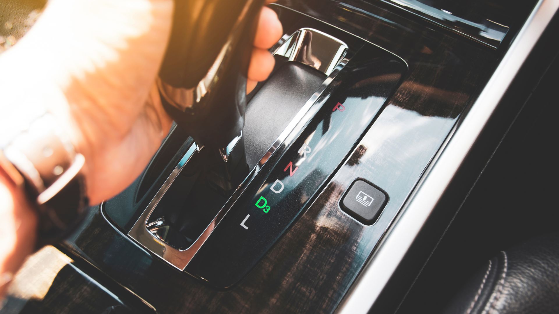 a person holding a remote control in their hand.|a close up of a gear stick in a car.|a close up of a gear stick in a car.