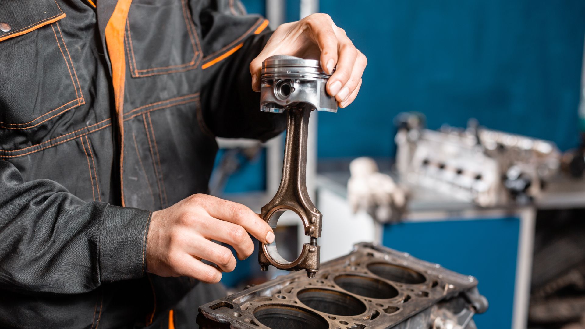 a man working on a car engine in a garage.|a close up of a person working on an engine.