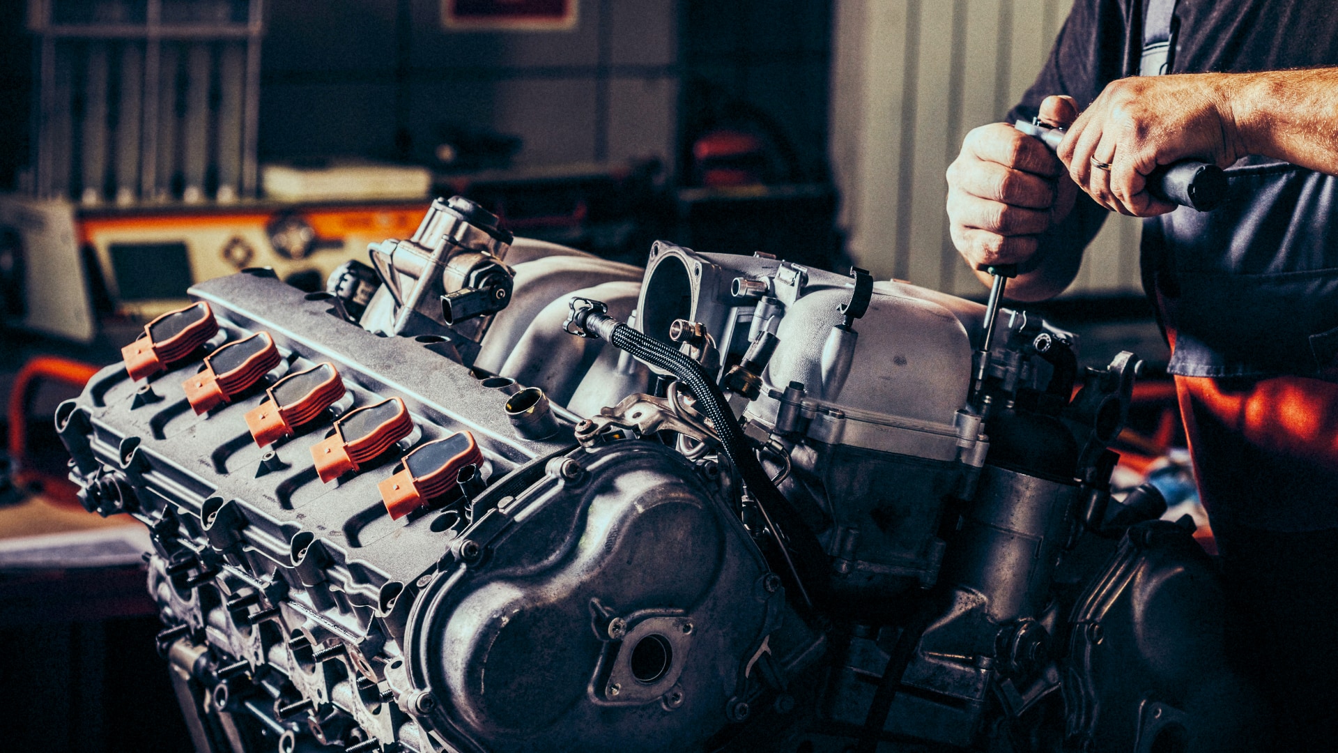 A man is working on a car engine in a garage.|A white car with blue numbers on the hood.