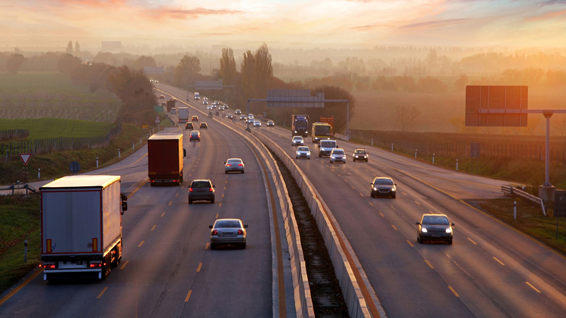 a highway filled with lots of traffic at sunset.|a white van driving down a road at night.