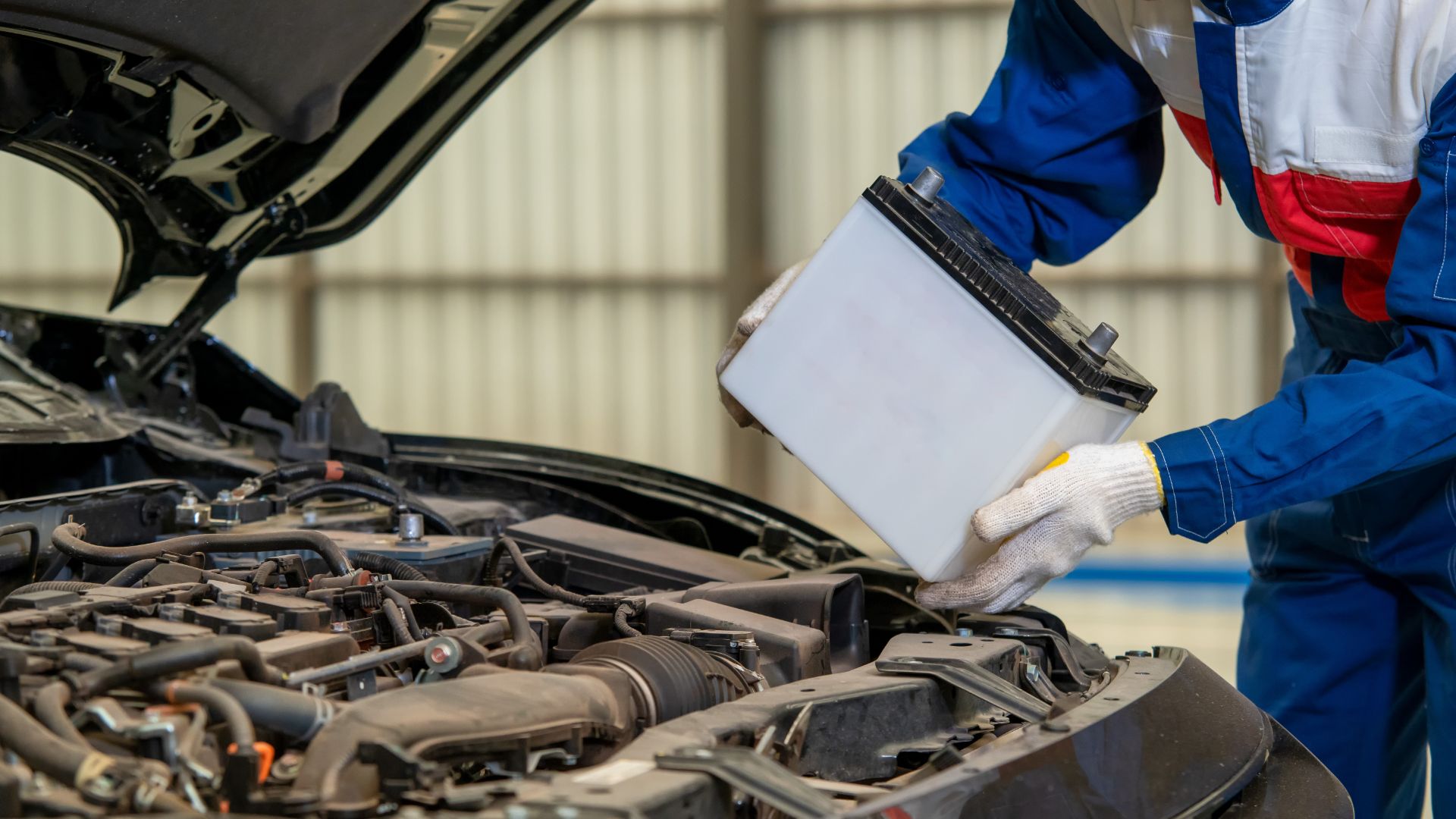 a mechanic working on a car engine in a garage.|a man is working on a car engine.|a close up of a car's engine compartment.|a man working on a car in a garage.