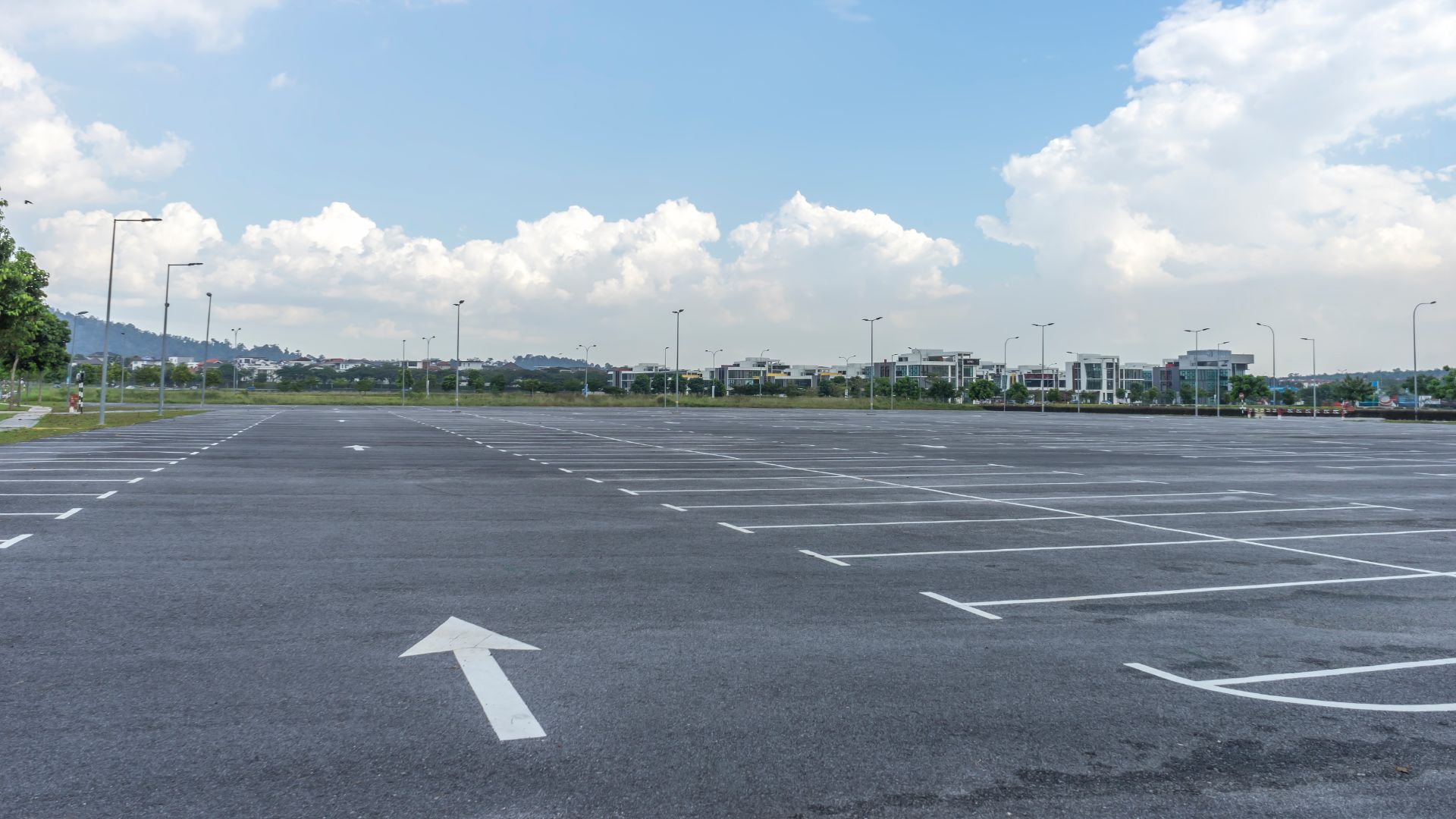 an empty parking lot with an arrow painted on it.|a speed limit sign on a pole in a parking garage.|a yellow slow down speed limit sign in a parking garage.|a car that is on its side in a parking lot.