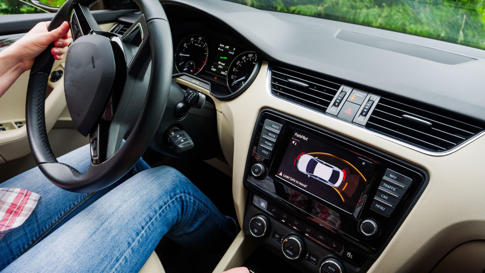 a person sitting in a car holding a steering wheel.
