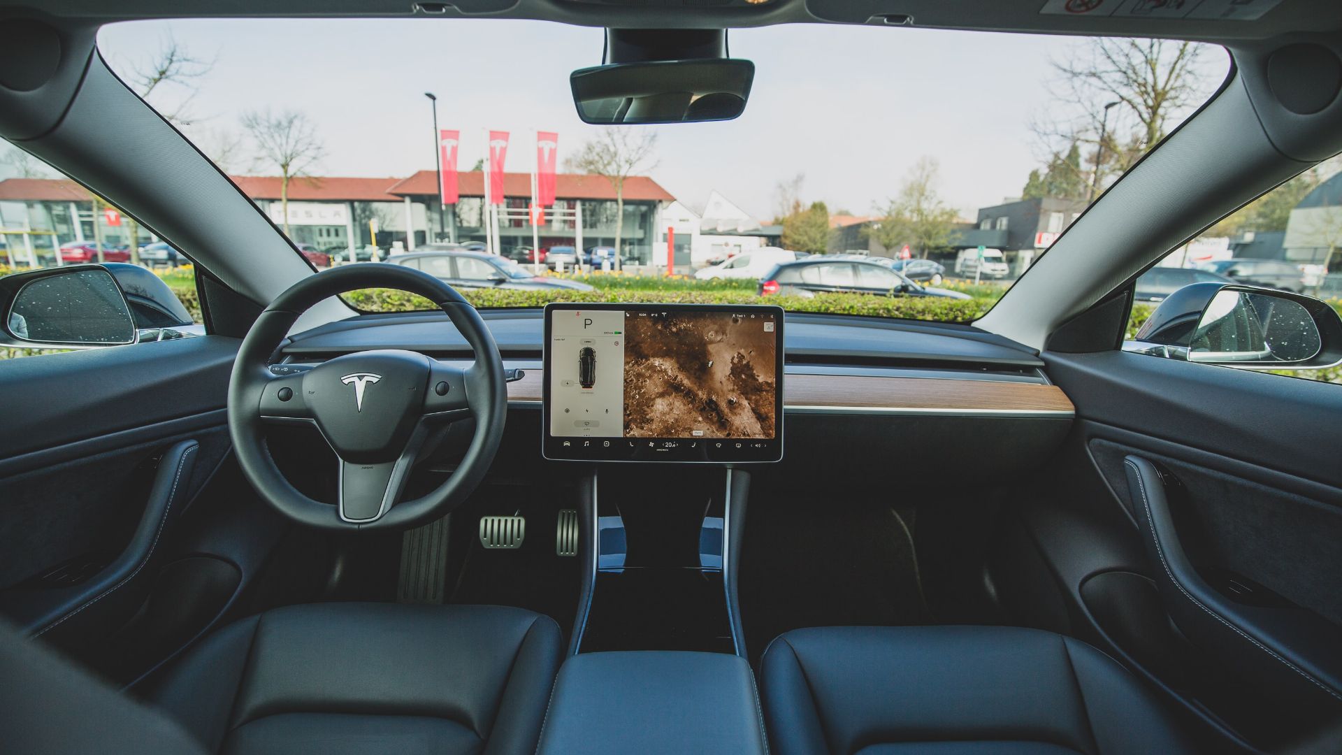 a car dashboard with a laptop on the dashboard.|a white car parked on the side of a road.