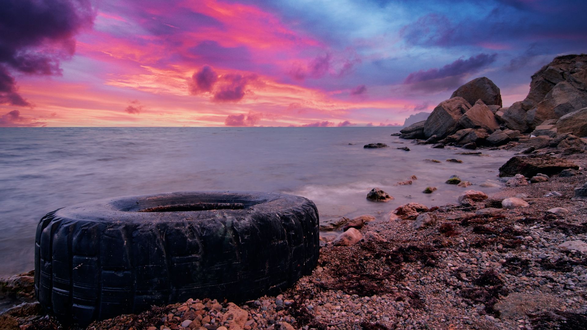 a tire sitting on top of a rocky beach.