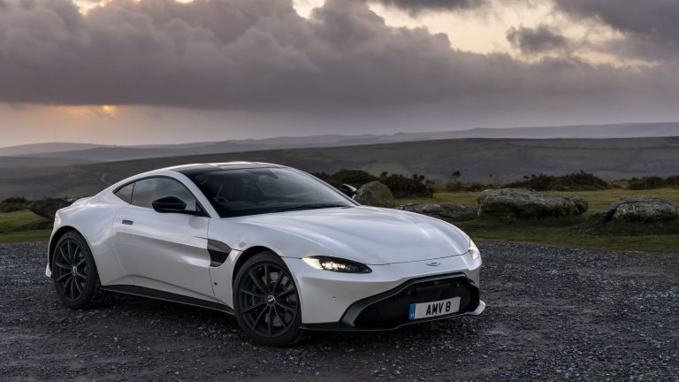 a white sports car parked on a gravel road.