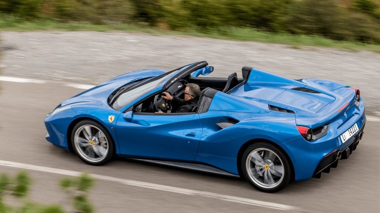 a blue sports car driving down a road.