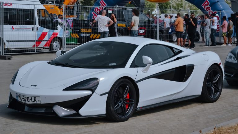 a white sports car parked in front of a crowd of people.