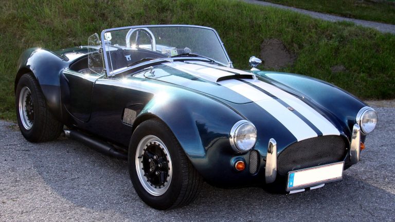 a blue and white sports car parked on a gravel road.