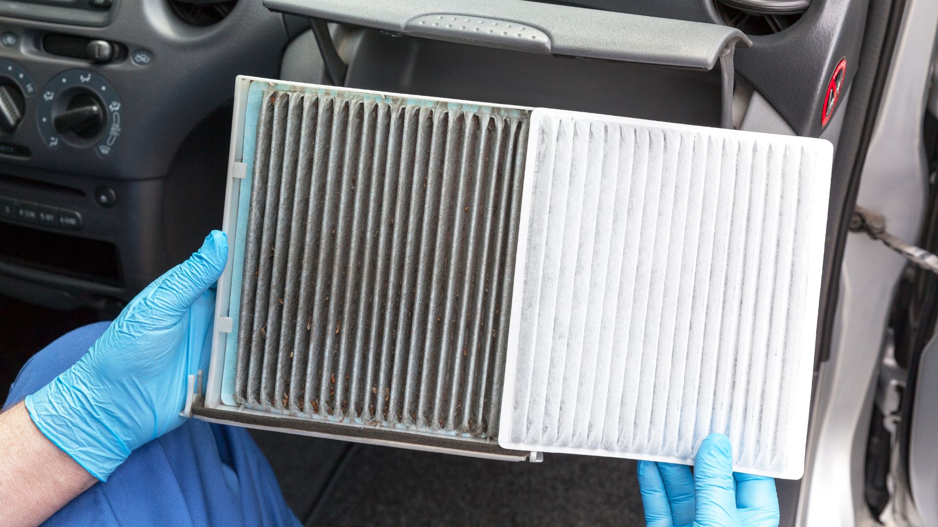 a person in blue gloves holding up a air filter.