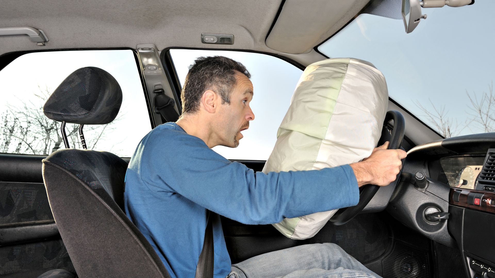 a man sitting in a car holding a pillow.