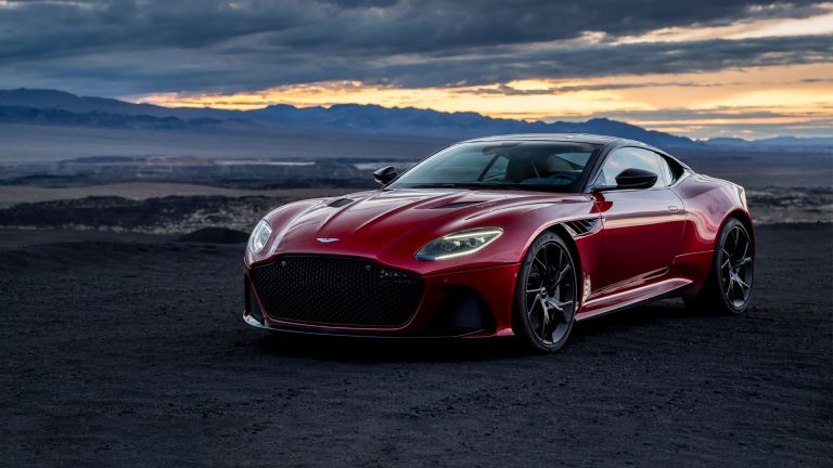 a red sports car parked on a dirt road.