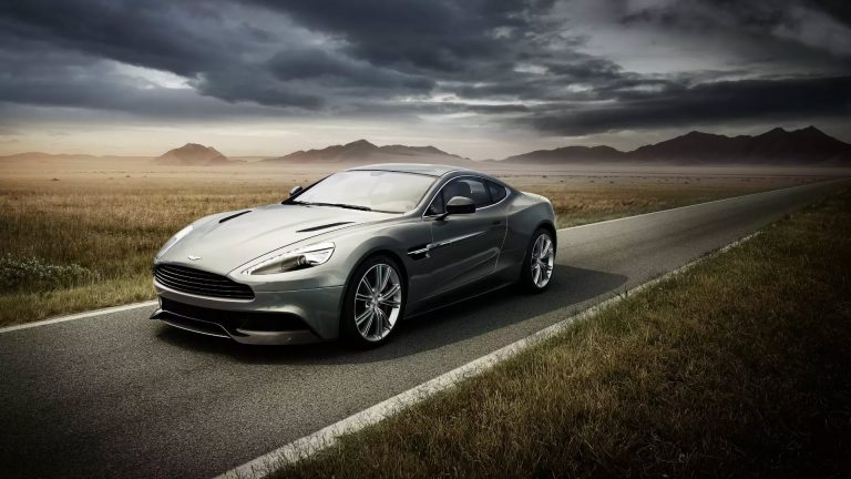 a silver car driving down a road under a cloudy sky.