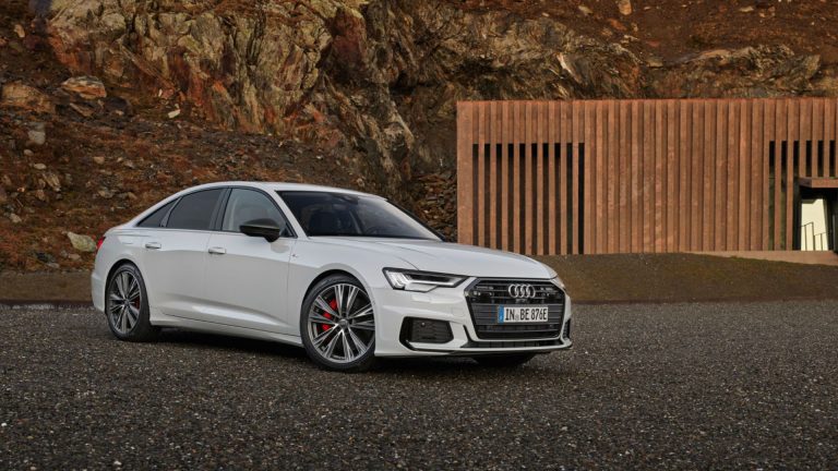 a white car parked in front of a mountain.