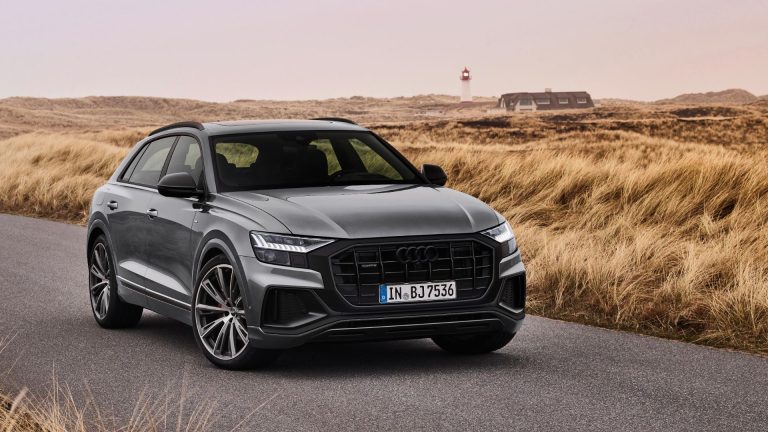 a grey audi suv driving down a country road.