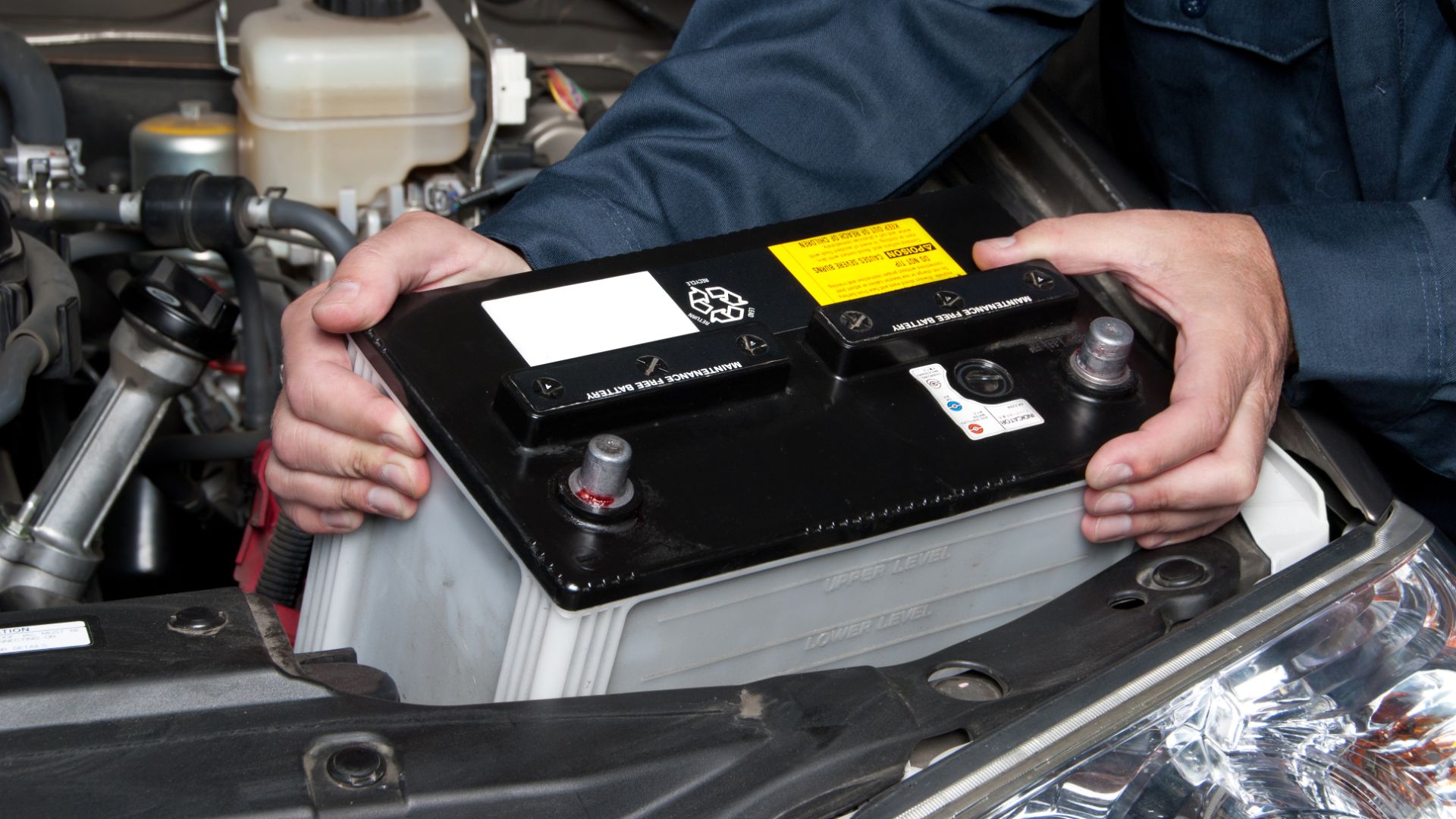 a man holding a car battery in his hands.