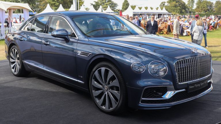 a blue car parked in front of a crowd of people.