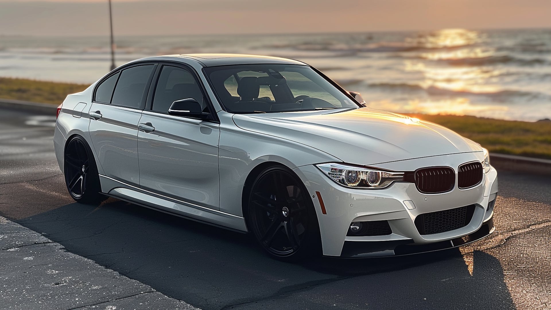 A white BMW 335i parked in front of the ocean.