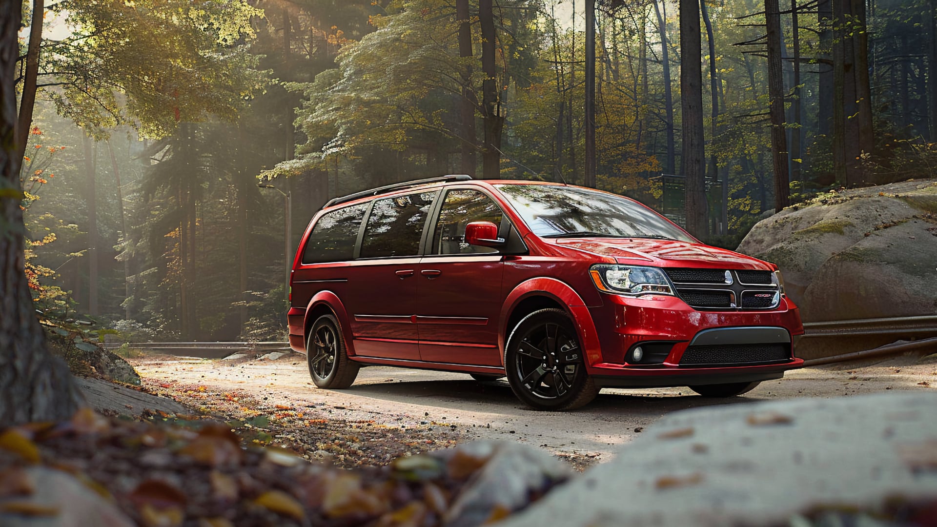 A red 2019 Dodge Grand Caravan parked in the woods.