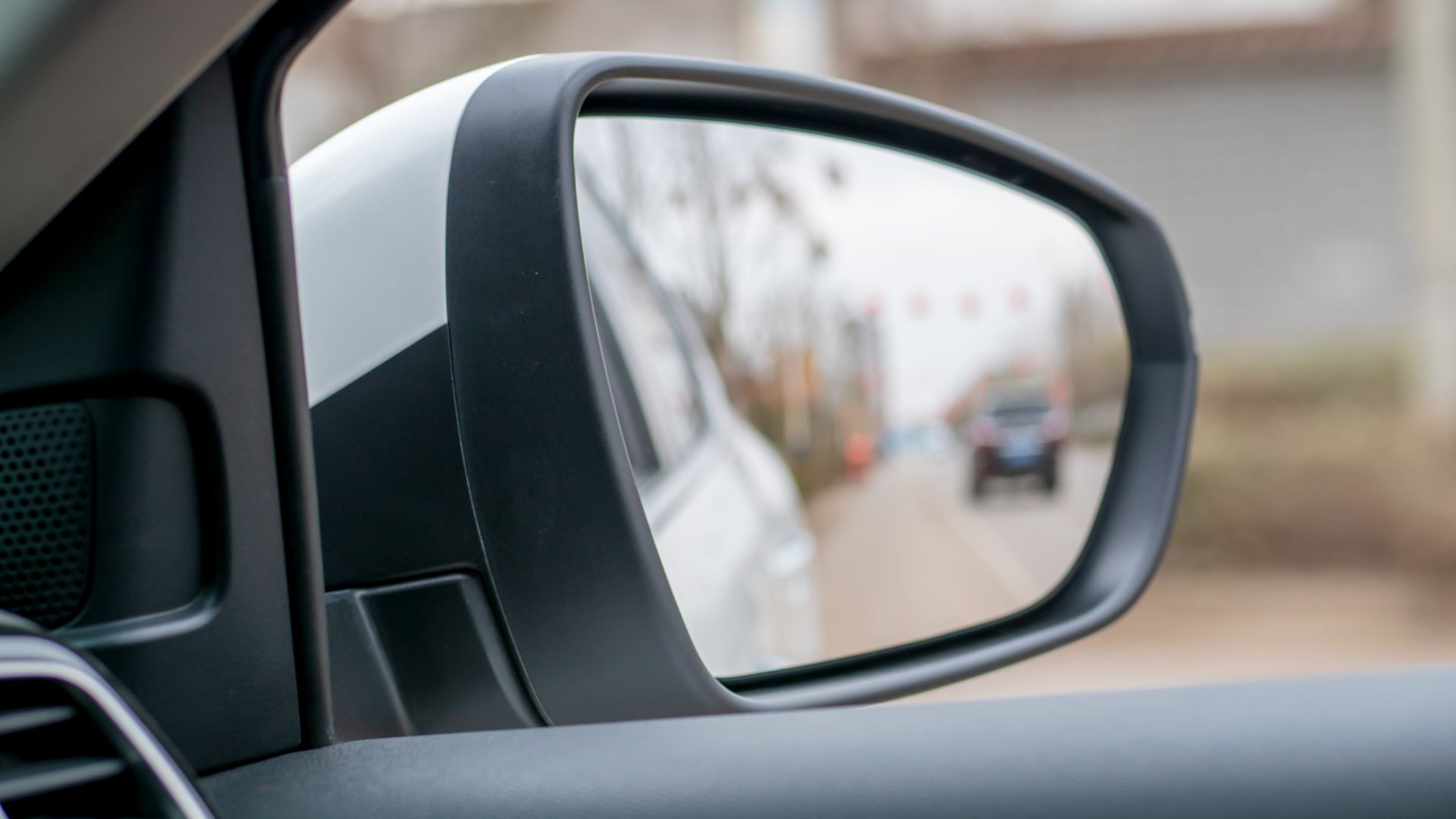 a side view mirror of a car with a street in the background.