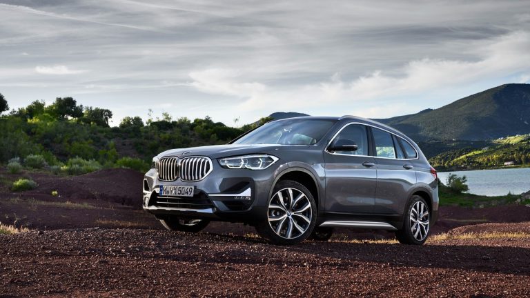 a silver bmw suv parked on a dirt road.