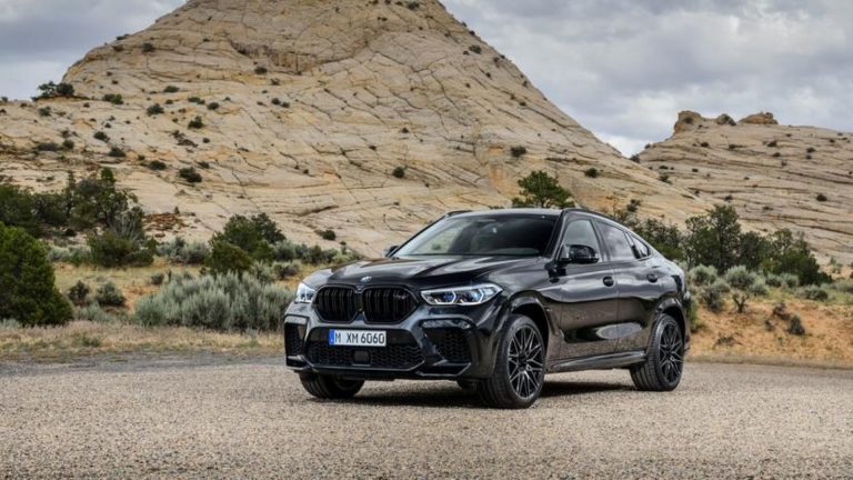 a black bmw suv parked in front of a mountain.