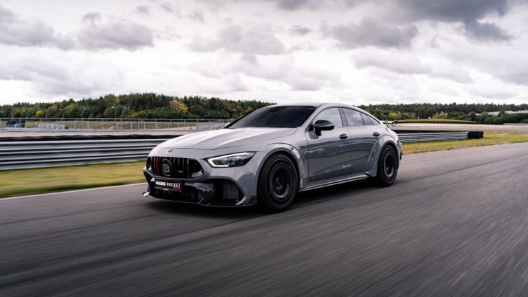 a silver car driving down a race track.