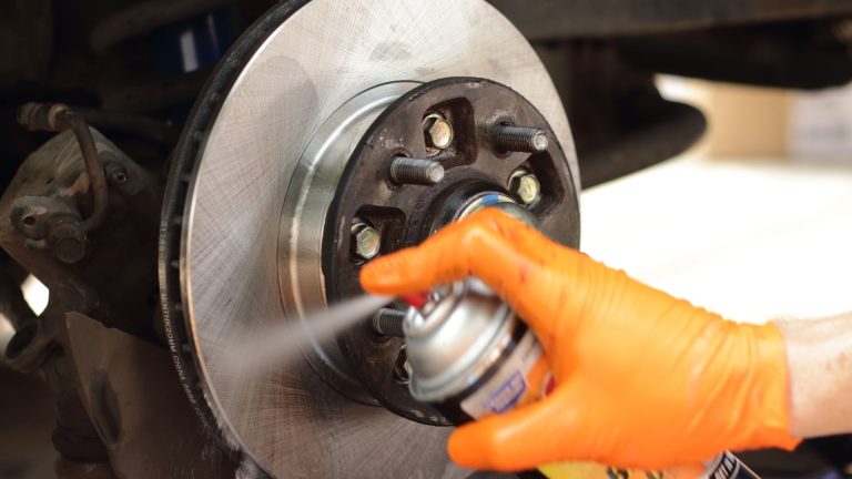 a person sprays down a brake on a car.