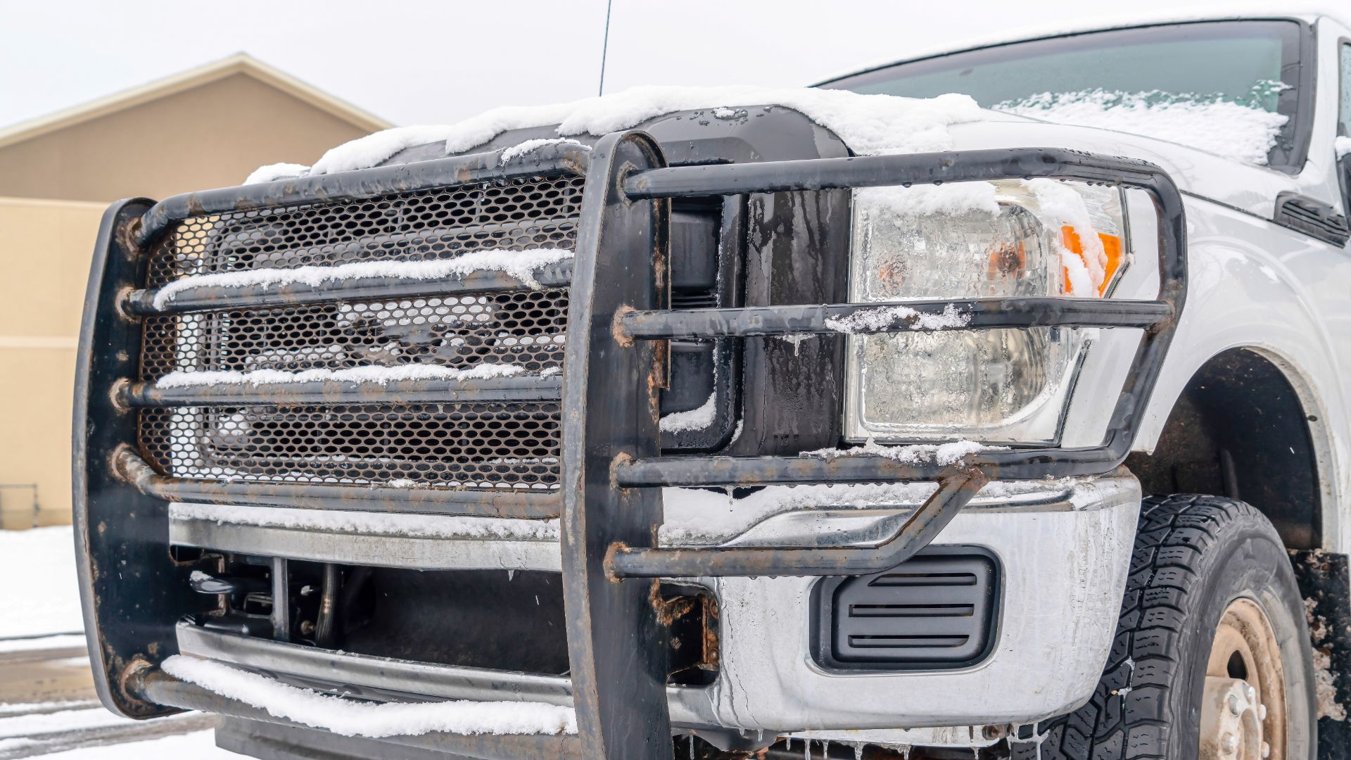 the front of a white truck covered in snow.