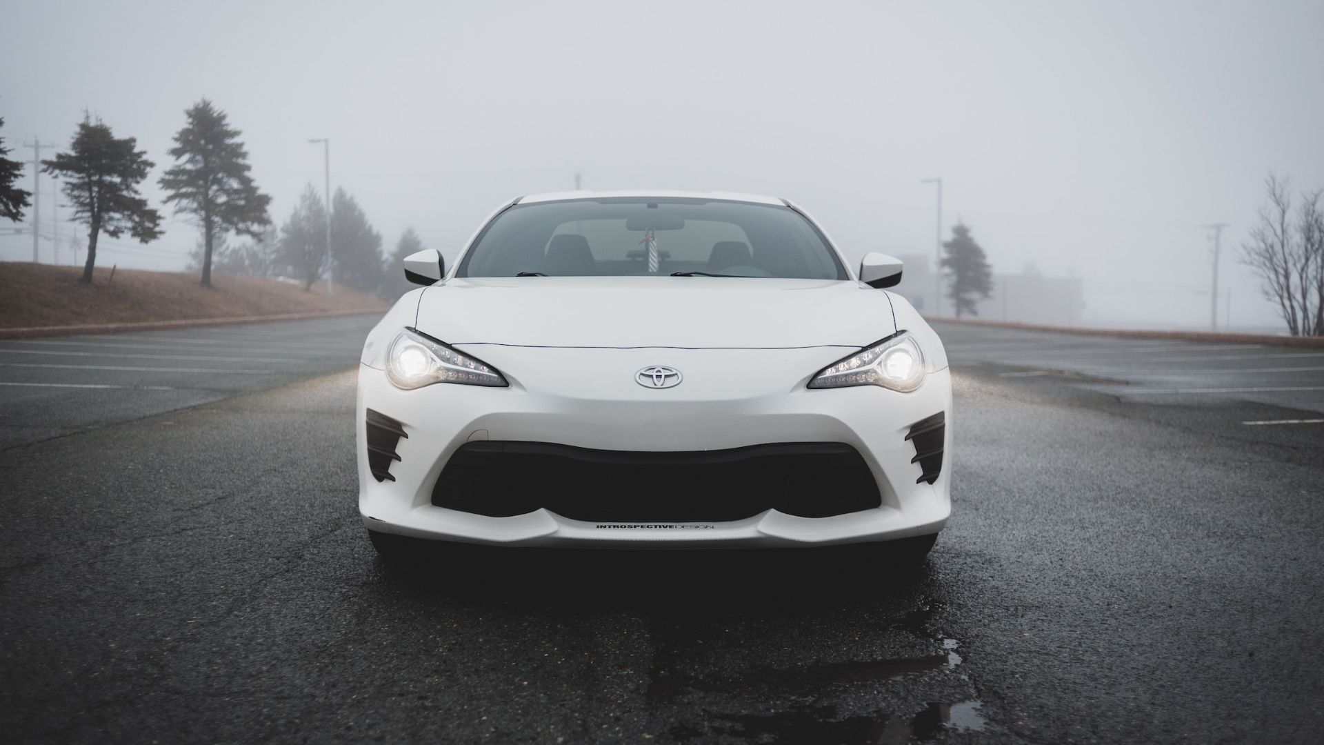 a white sports car parked in a parking lot.