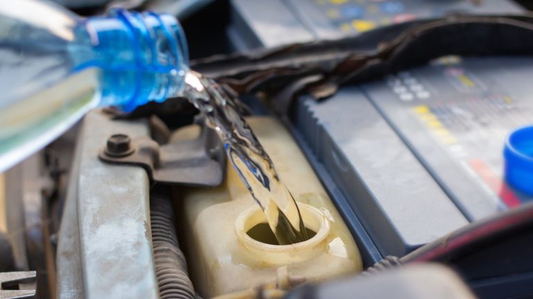 a close up of a car's engine with a water bottle.