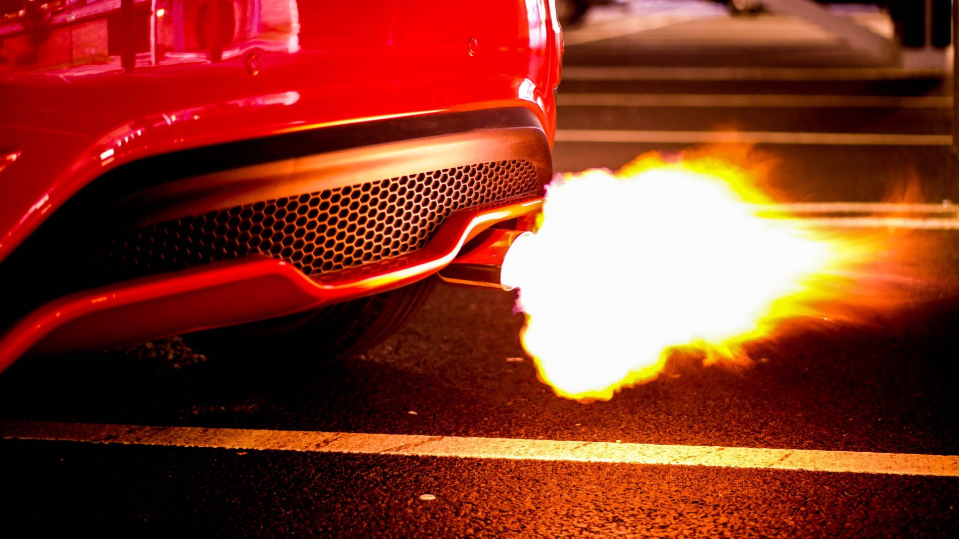 a close up of a red car with a lot of fire coming out of it.