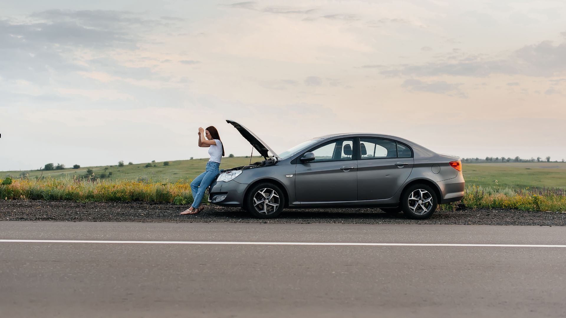 a woman standing next to a car on the side of the road.