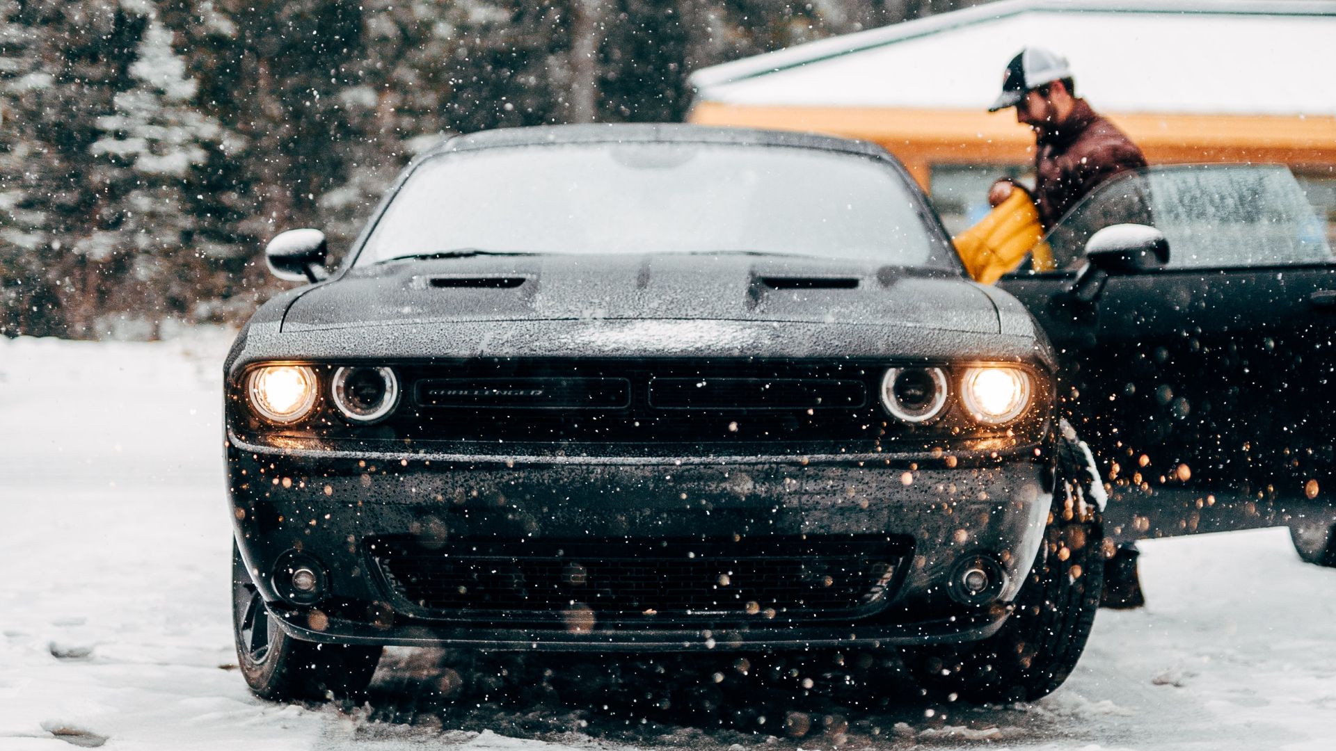 a black dodge truck driving down a snow covered road.