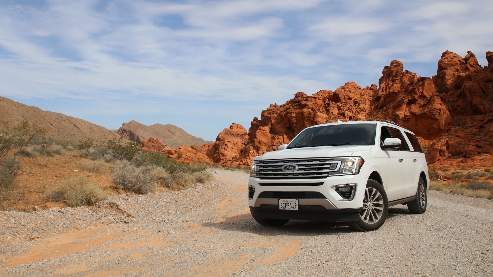 a white suv is parked on a gravel road.