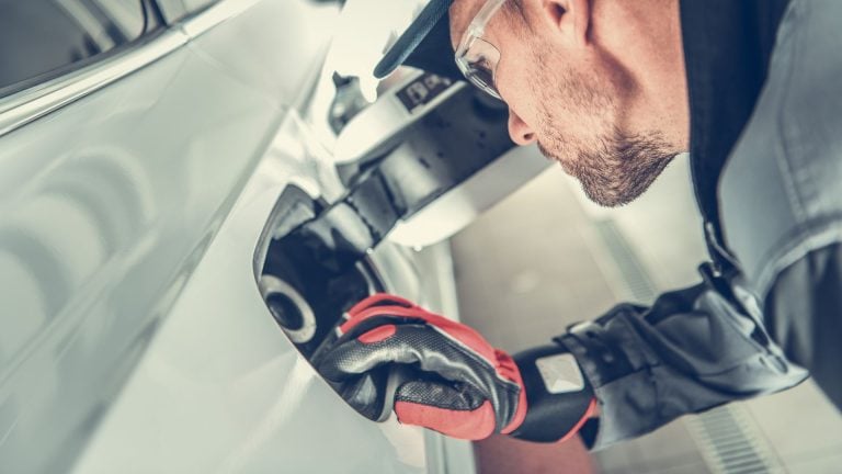 a man wearing a helmet and gloves working on a car.