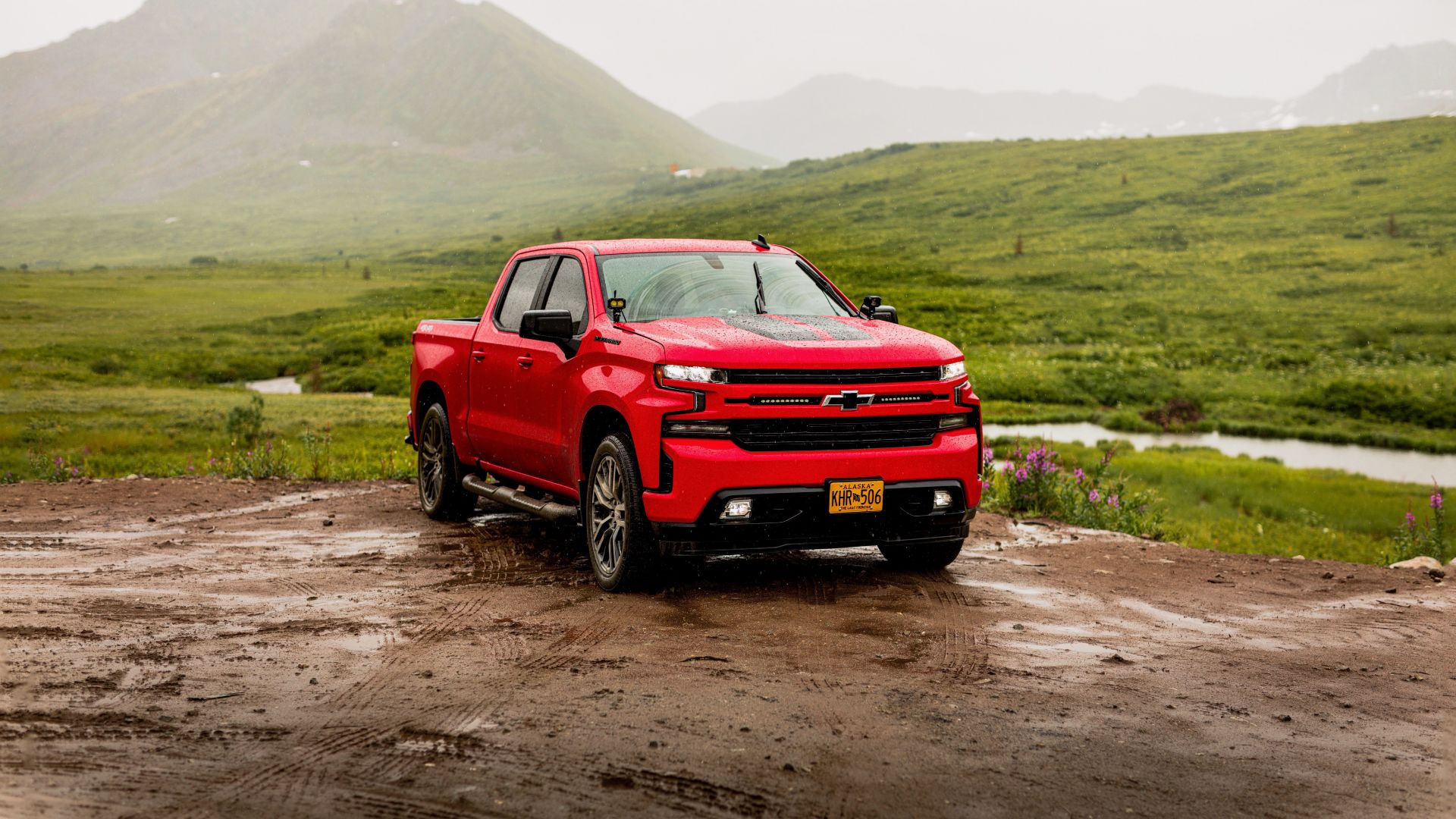 a red truck is parked on a muddy road.