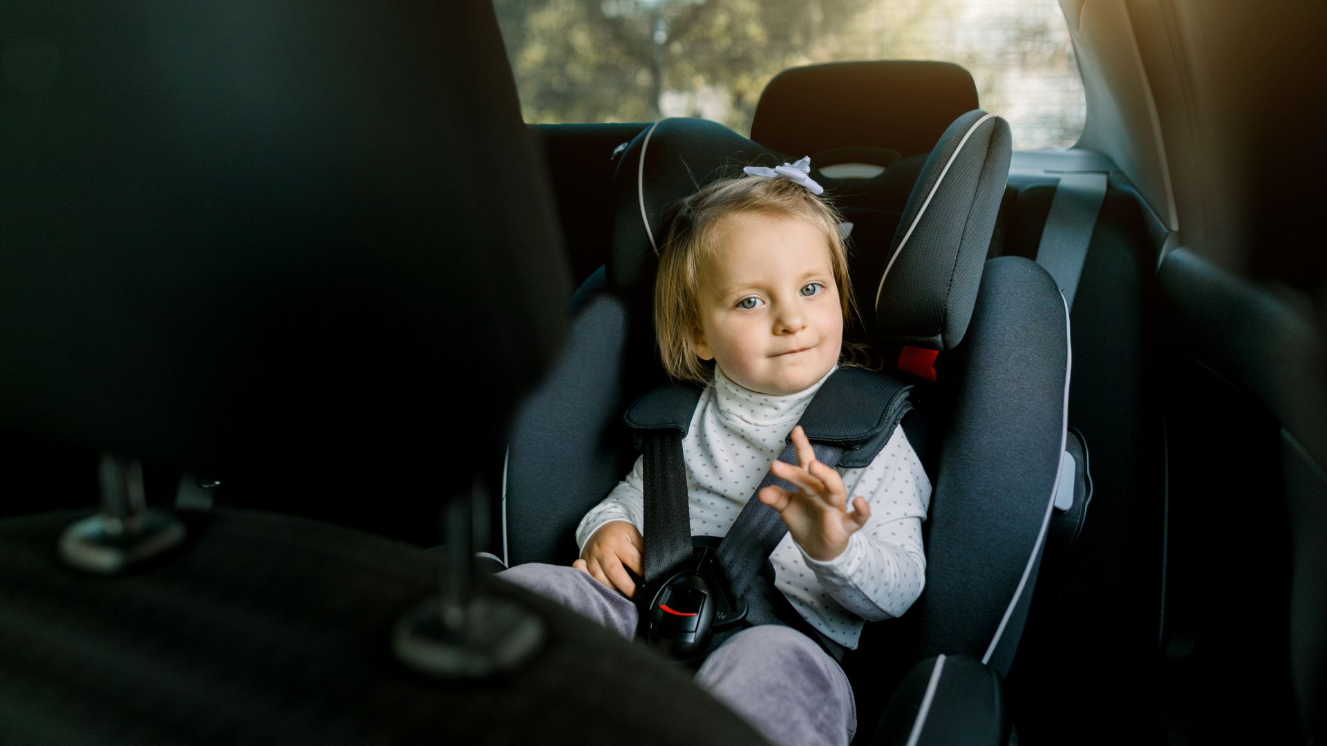 a little girl sitting in a car seat.