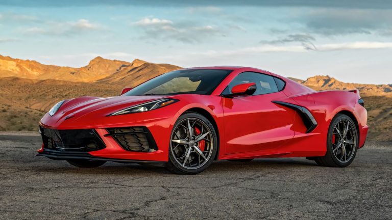 a red sports car parked in front of mountains.