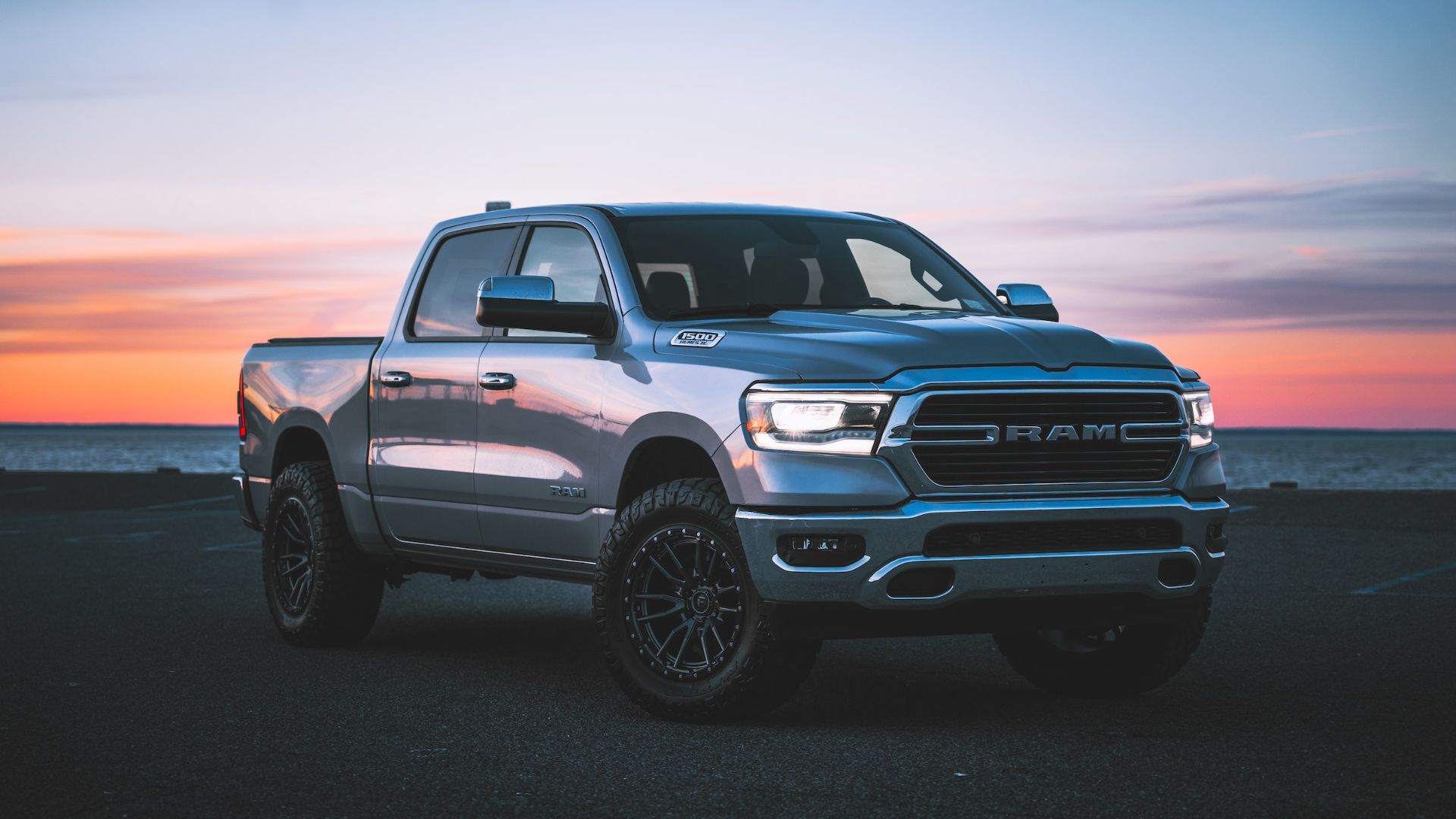 a silver ram truck parked in front of a sunset.