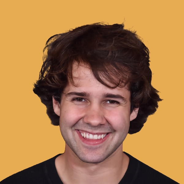 A man with curly hair smiling in front of a yellow background.