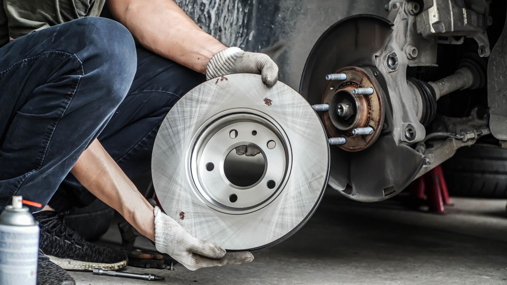 a man working on a brake assembly on a car.