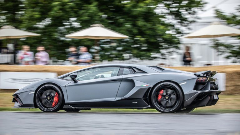 a grey sports car driving down a race track.