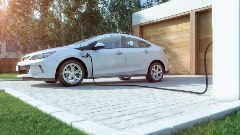 a white car plugged in to a charging station.